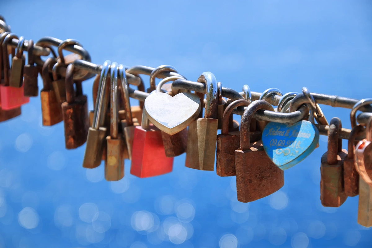 Many padlocks on a chain over a blue sky background.