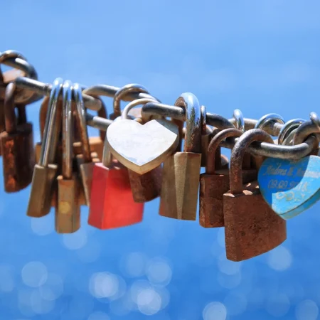 Many padlocks on a chain over a blue sky background.
