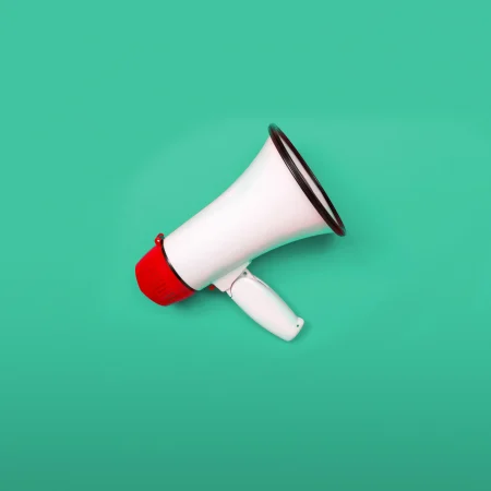 White and red bullhorn on a mint green background.
